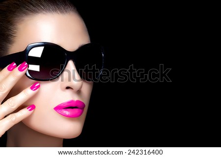 Beautiful fashion model face with oversized black sunglasses. Bright makeup and manicure. High fashion portrait isolated on black background with copy space for text. Beauty and fashion concept.