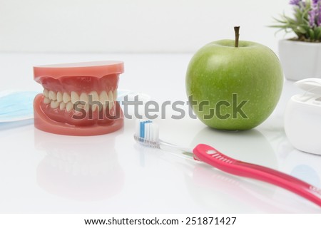 Tooth shape. The teeth of the upper and lower jaw with toothbrush and an apple and flossing In the background is a flower.