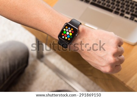 Hand wearing elegant Smart Watch, with different apps. In the background is a notebook.