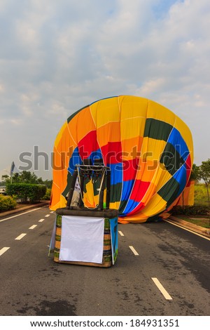 A hot air balloon landed on the middle of the road.