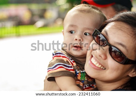 Young asian mom with her baby outdoors. Shallow dof, selective focus on mother.