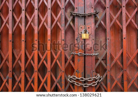 Locked rusty old red gate., Mean is Security