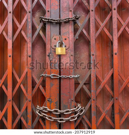 Locked rusty old red gate., Mean is Security