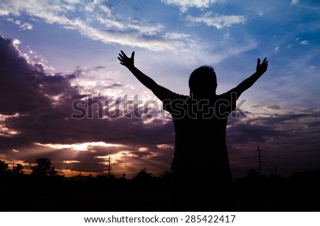 Silhouette of woman on a summit with upraised arms  with the sunset, Praise for GOD.