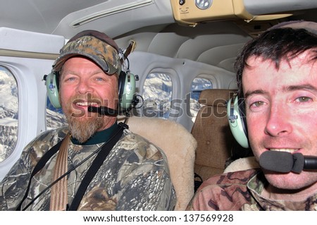 hunters in camouflage in a light aircraft over the Southern Alps of New Zealand