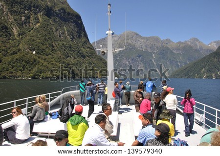 MILFORD SOUND, NEW ZEALAND, JANUARY 8: Passengers crowd the deck of a tourist launch on January 8, 2011 at Milford Sound, New Zealand. Milford is one of the country's favourite tourist destinations.