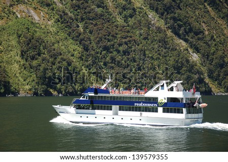 MILFORD SOUND, NEW ZEALAND, JANUARY 8: A small tourist launch carries passenfers on January 8, 2011 at Milford Sound, New Zealand. Milford is one of the country\'s favourite tourist destinations.
