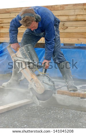 Builder cuts edge of concrete slab with diamond saw blade concrete cutter