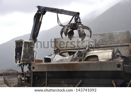 GREYMOUTH, NEW ZEALAND-AUGUST 12: Unidentified man feeds an old vehicle into a steel compacting unit for recycling, on  August 12, 2008 near Greymouth, New Zealand