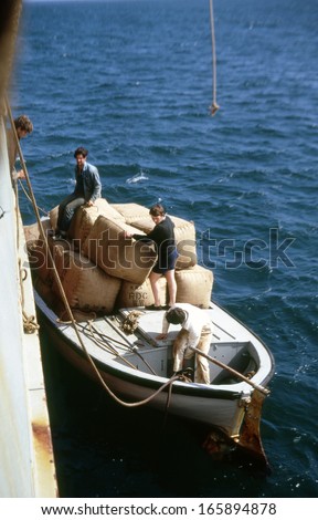 CHATHAM ISLANDS, SOUTH PACIFIC, CIRCA 1960: People transfer bales of wool from a small boat to the Holmdale for shipment to New Zealand circa 1960 in the Chatham Islands, South Pacific