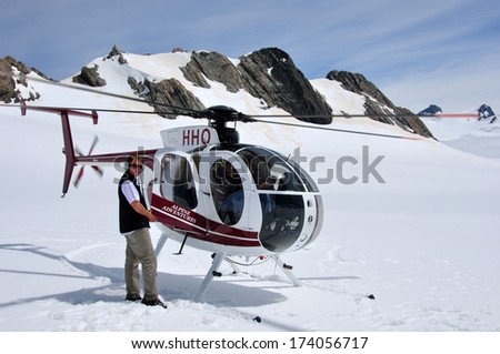 FRANZ JOSEF GLACIER, NEW ZEALAND: DECEMBER 24, 2009: Pilot welcomes passengers aboard his helicopter on the snow above Franz Josef Glacier, Westland, New Zealand