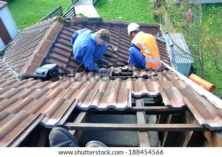 GREYMOUTH, NEW ZEALAND, APRIL 17, 2014: Volunteer workers replace tiles on a house damaged in Cobden by Cyclone Ita, Greymouth, New Zealand, April 17, 2014