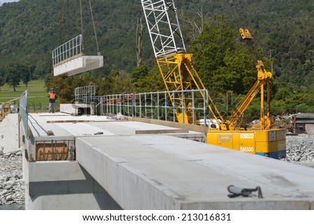 GREYMOUTH, NEW ZEALAND, CIRCA DECEMBER 2013: Builders construct a concrete bridge over a small river in Westland, New Zealand