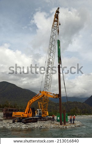 GREYMOUTH, NEW ZEALAND, CIRCA DECEMBER 2013: Builders drive pylons as they construct a concrete bridge over a small river in Westland, New Zealand
