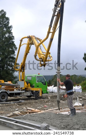 Builder uses a concrete pump to direct wet concrete into the foundations of a large building