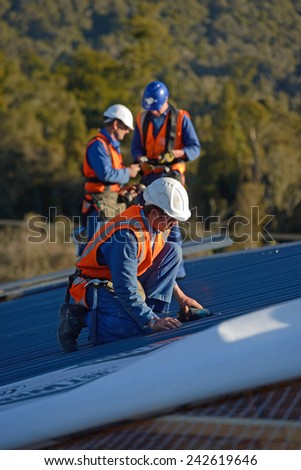 GREYMOUTH, NEW ZEALAND, SEPTEMBER 6, 2014: A team of contractors put the roof on a large commercial building near Greymouth, New Zealand, September 6, 2014