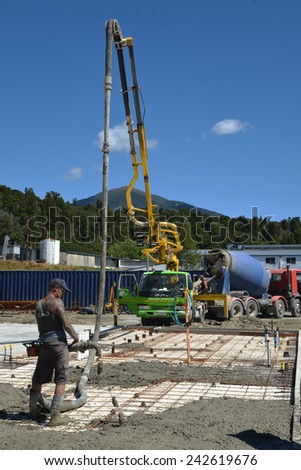 GREYMOUTH, NEW ZEALAND, FEBRUARY 2, 2014: Builder uses a concrete pump to direct wet concrete into the foundations of a large building near Greymouth, South Island, New Zealand, February 2, 2014