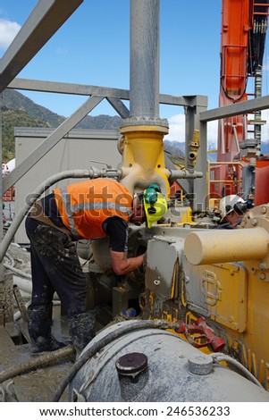 WHATAROA, NEW ZEALAND, DECEMBER 5, 2014: An unidentified driller on the Deep Fault Drilling Project cleans a mud pump during a break while drilling to 1300 metres near Whataroa, New Zealand
