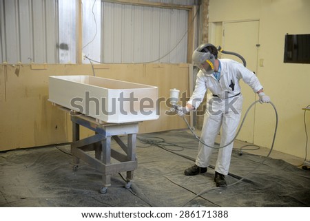 Tradesman spray painting a coffin in a spray booth