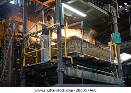 GREYMOUTH, NEW ZEALAND, MAY 22, 2015 : worker stacks freshly made  untrimmed sheets of plywood on May 22, 2015, near Greymouth, New Zealand