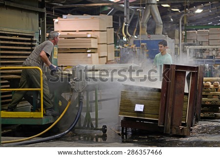 GREYMOUTH, NEW ZEALAND, MAY 22, 2015 : workers stack freshly made  untrimmed sheets of plywood on May 22, 2015, near Greymouth, New Zealand