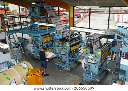 GREYMOUTH, NEW ZEALAND, MAY 22, 2015:  An unidentified printer checks the quality of his workmanship while printing a newspaper on May 22, 2015 in Greymouth, New Zealand.