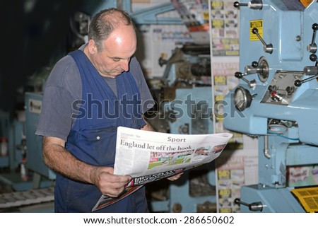 GREYMOUTH, NEW ZEALAND, MAY 22, 2015:  An unidentified printer checks the quality of his workmanship while printing a newspaper on May 22, 2015 in Greymouth, New Zealand.