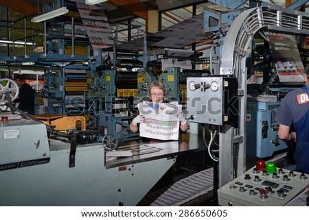 GREYMOUTH, NEW ZEALAND, MAY 22, 2015:  An unidentified woman bundles up newspapers as they are printed on May 22, 2015 in Greymouth, New Zealand.