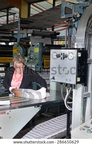 GREYMOUTH, NEW ZEALAND, MAY 22, 2015:  An unidentified woman bundles up newspapers as they are printed on May 22, 2015 in Greymouth, New Zealand.