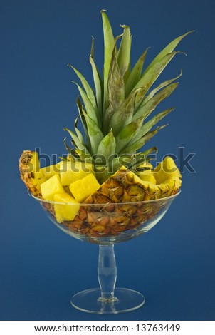 Pineapple branch and slices in a glass dish.