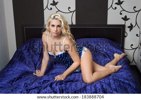 Young blond girl in erotic lingerie posing in the interior