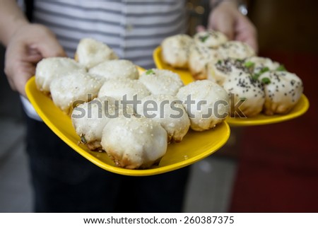 Hands holding traditional Chinese soup pork dumpling - which is a popular Chinese dim sum cooked by fried