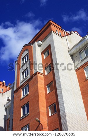 Photo of big business house from white and red brick against dark blue sky with clouds