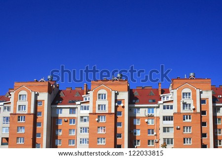 Photo of big interesting brick house with red roof against blue sky