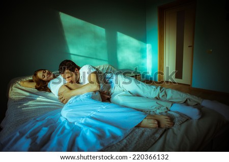 Image of happy future dad kiss the belly of his cheerful caucasian pregnant wife lying on bed at home.