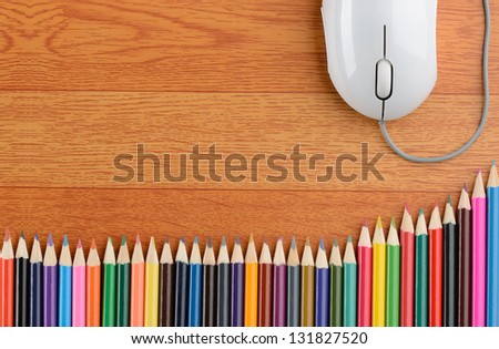 Back to school color pencils and a computer mouse on wood background