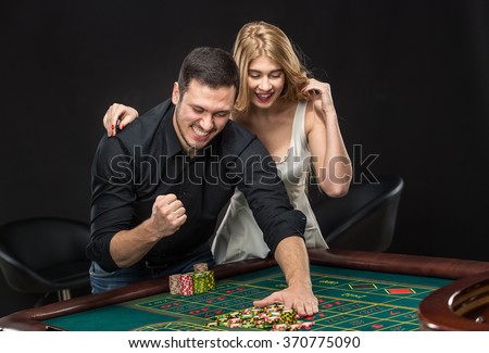 Young couple celebrating win at roulette table in casino.