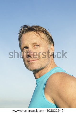 Handsome sportsman with stubble wearing a blue tank top.