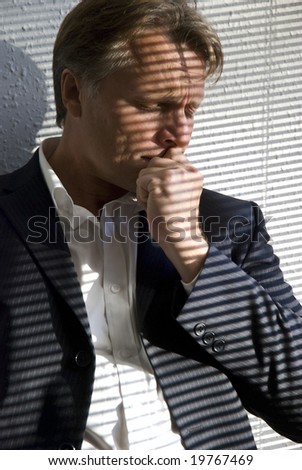 a stressed and upset businessman is standing in the corner of his office next to a window