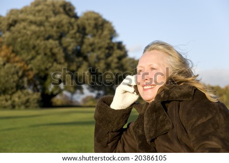 A beautiful sixties lady has a friendly chat on her cellphone while sitting in the park