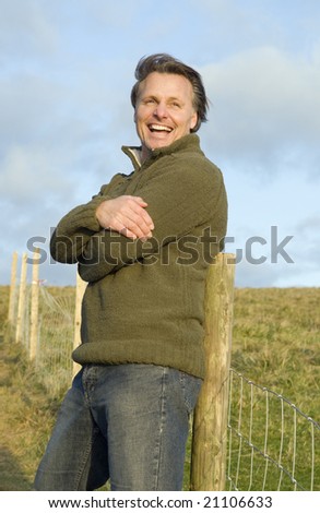 A handsome forties man takes a brief rest during a walk in the countryside.He has a wonderful smile.