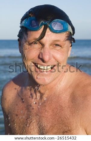 A handsome forties man wearing swimming goggles is laughing as water falls of his head. - stock-photo-a-handsome-forties-man-wearing-swimming-goggles-is-laughing-as-water-falls-of-his-head-26515432