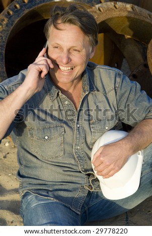 A portrait of a happy smiling builder on cellphone.