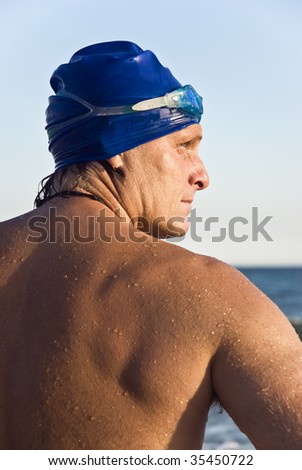A color portrait of a swimmer wearing blue cap and goggles.