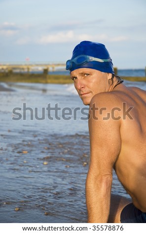 A mature macho looking swimmer wearing swim cap and goggles.