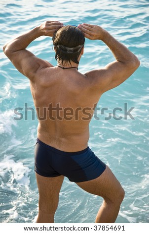 Colour photo of the back view of a muscular male swimmer.