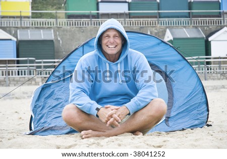 A happy mature man camping on the beach.