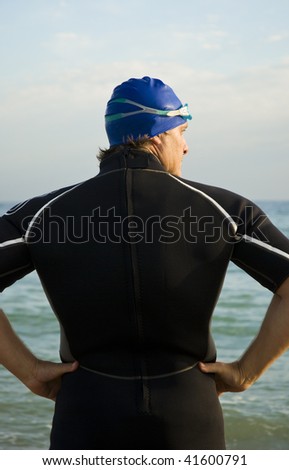 A back view of a muscular male triathlete or swimmer looking to the side