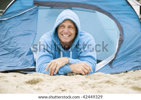 A color portrait photo of a happy mature forties man camping on the beach.