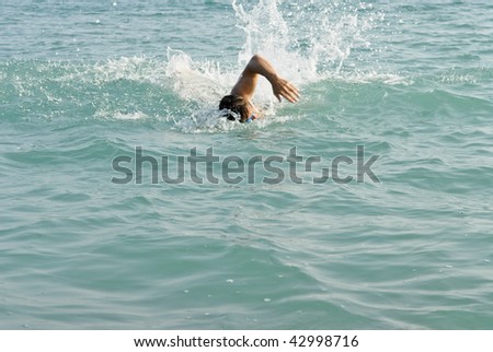 A man swimming front crawl in the sea.